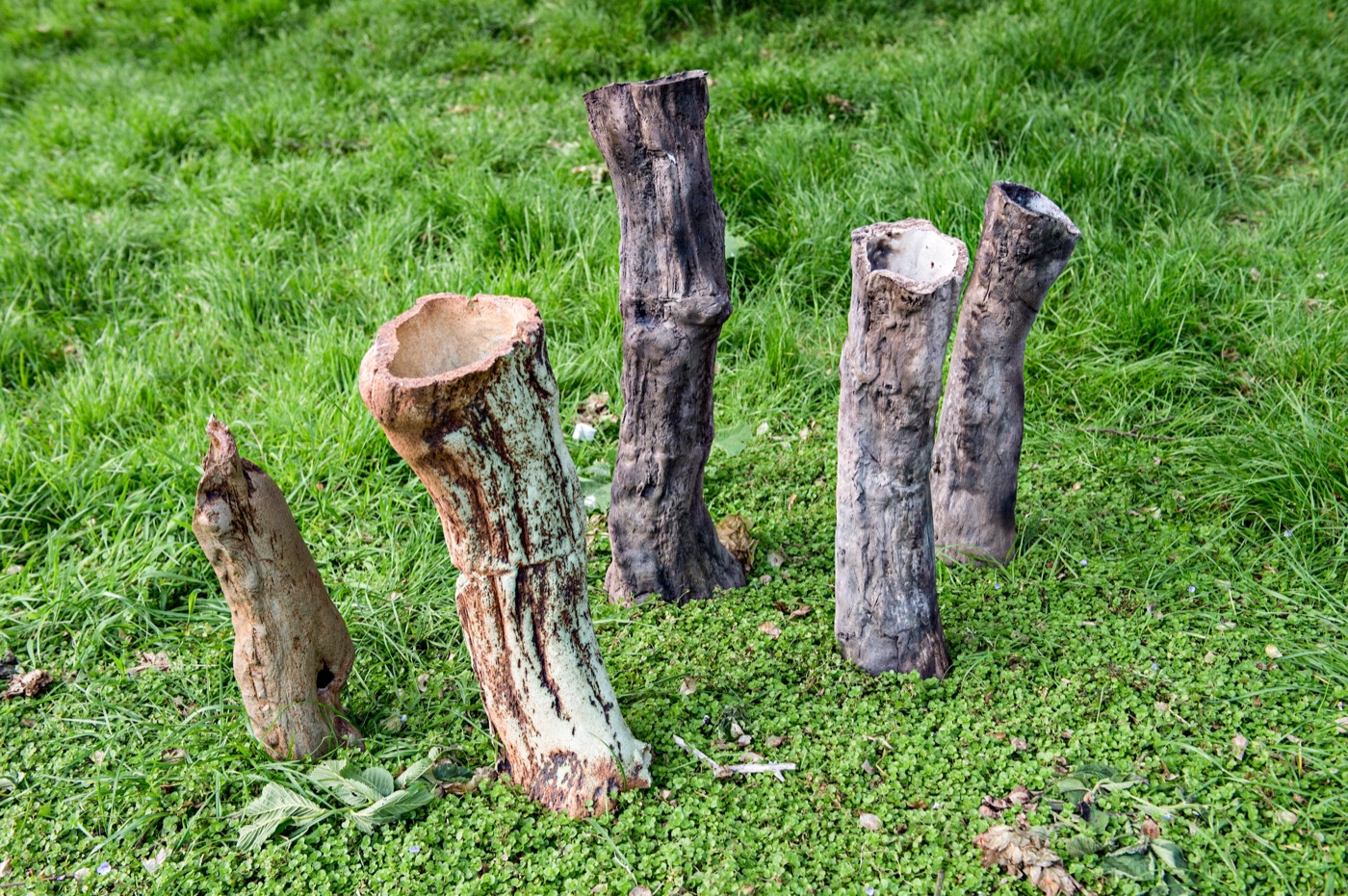 Smoke-fired ceramic tree trunks standing in grass