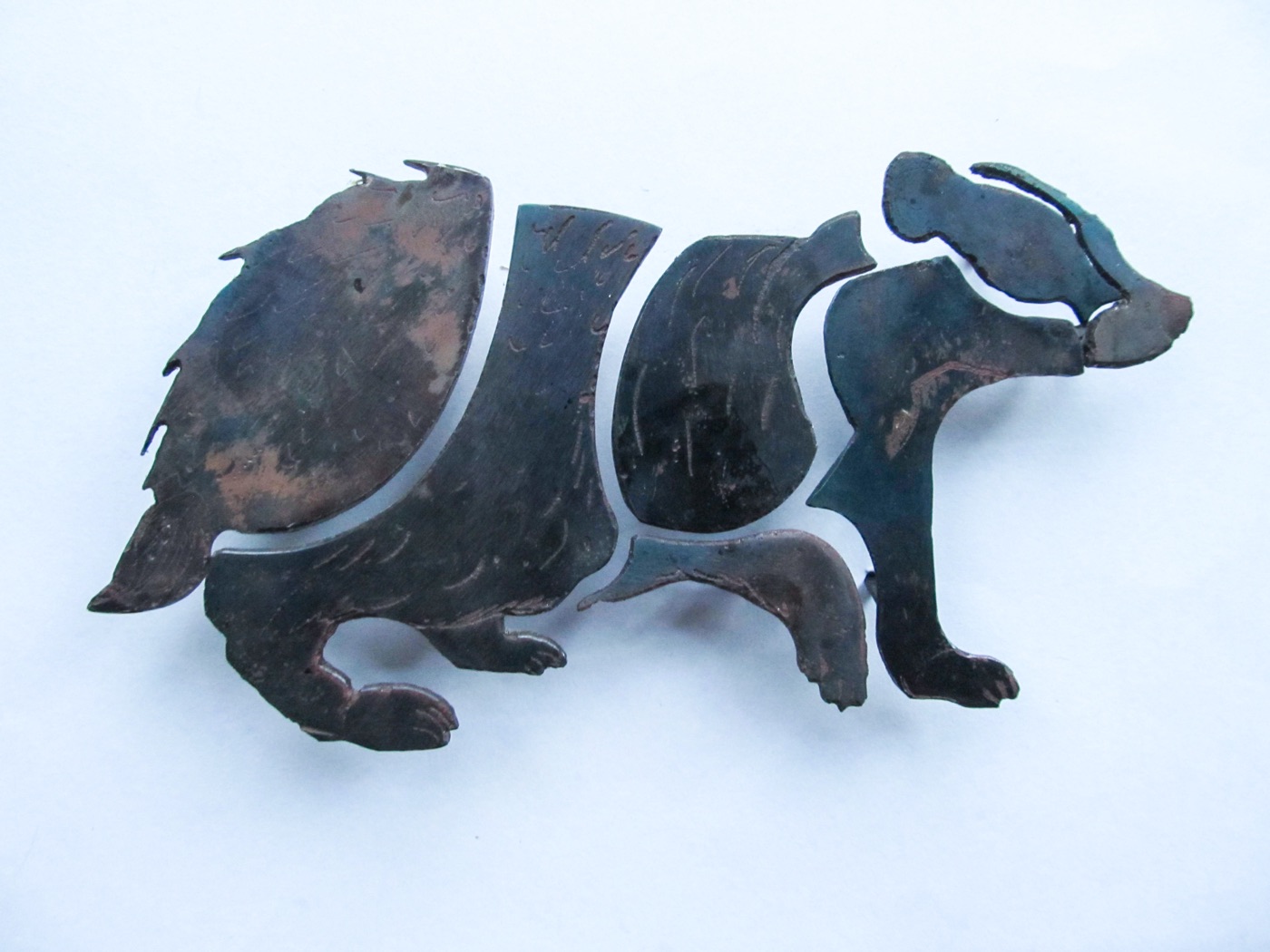 Hand-cut metal badger made of separate pieces