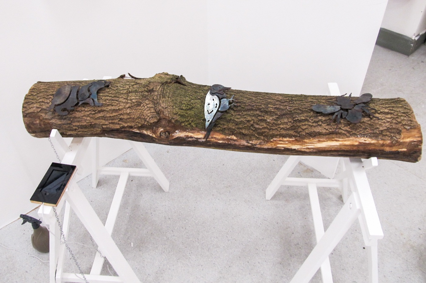 Metal creatures mounted along a reclaimed log