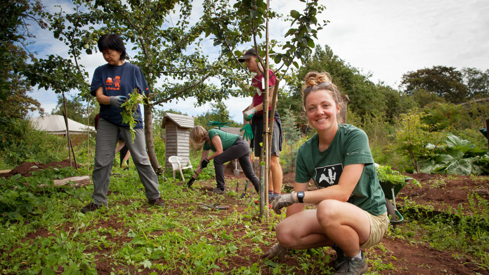 Rosa planting a young apple tree with volunteers at Grow Wilder
